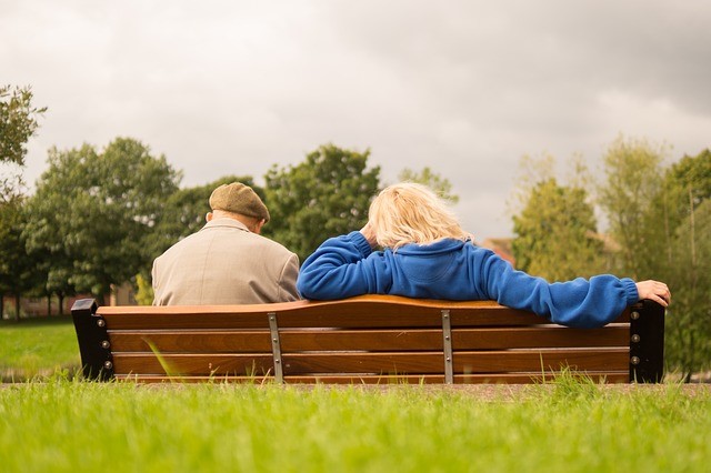 Rückenansicht eines Paares, das auf einer Parkbank sitzt